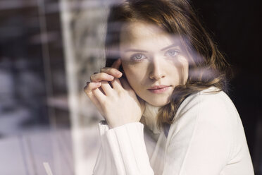 Porträt einer jungen Frau, die durch die Fensterscheibe eines Cafés schaut - GDF000508
