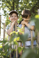 Porträt von zwei lächelnden Jungen, die hinter einem Holzzaun stehen - FKIF000041