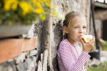 Porträt eines lächelnden kleinen Mädchens, das einen Apfel isst - FKIF000047