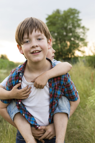 Portrait of smiling little boy giving his brother piggy back stock photo