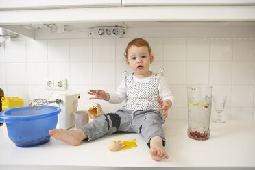 Kleines Mädchen sitzt auf Küchentisch mit zerbrochenem Ei - FSF000205