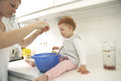 Mutter und kleine Tochter backen gemeinsam Kuchen in ihrer Küche, lizenzfreies Stockfoto