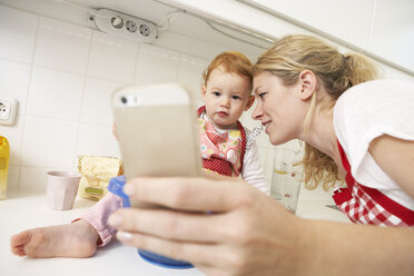 Young woman taking a selfie with her little daughter in their kitchen - FSF000217