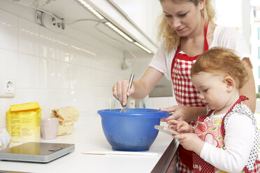 Mutter und kleine Tochter backen gemeinsam Kuchen in ihrer Küche - FSF000251