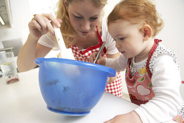Mutter und kleine Tochter backen gemeinsam Kuchen in ihrer Küche - FSF000243