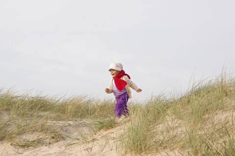 Glückliches kleines Mädchen läuft auf einer Stranddüne, lizenzfreies Stockfoto
