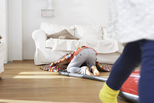 Junge im Wohnzimmer beim Staubsaugen unter dem Teppich - FSF000254