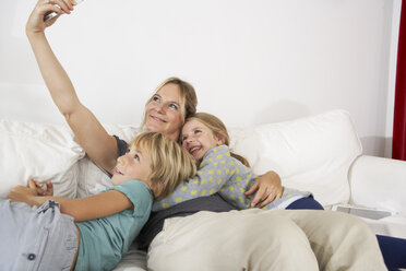 Happy mother, daughter and son on couch taking a selfie - FSF000286