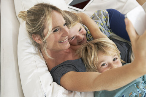 Glückliche Mutter, Tochter und Sohn auf der Couch machen ein Selfie - FSF000266
