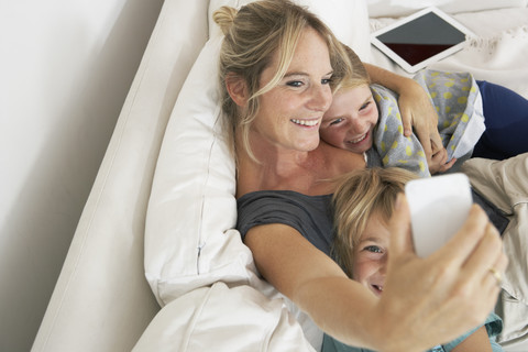 Happy mother, daughter and son on couch taking a selfie stock photo
