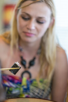 Junge Frau isst Sushi mit Essstäbchen - ABAF001535