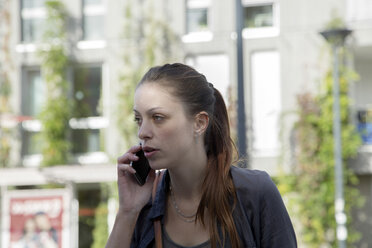 Porträt einer jungen Frau, die mit einem Smartphone telefoniert - SGF000871