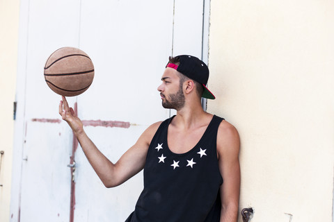 Junger Mann balanciert Basketball mit Basecap, lizenzfreies Stockfoto