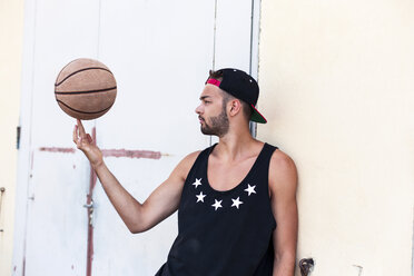 Junger Mann balanciert Basketball mit Basecap - DAWF000172