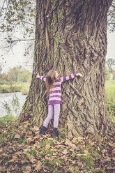 Kleines Mädchen, das einen alten Baum umarmt - SARF000933