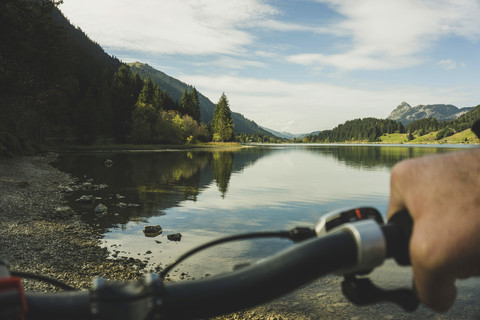 Österreich, Tirol, Tannheimer Tal, Mann auf Mountainbike am Seeufer, lizenzfreies Stockfoto