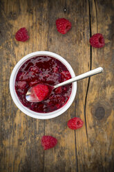 Bowl of red fruit jelly and raspberries on dark wood - LVF002068