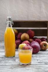 Bottle and glass of apple juice and red apples on wood - LVF002071