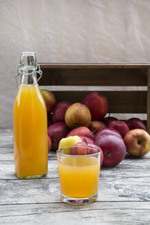 Flasche und Glas mit Apfelsaft und roten Äpfeln auf Holz - LVF002071