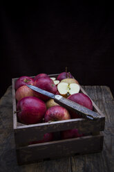 Wooden box of red apples and a pocket knife in front of black background - LVF002074