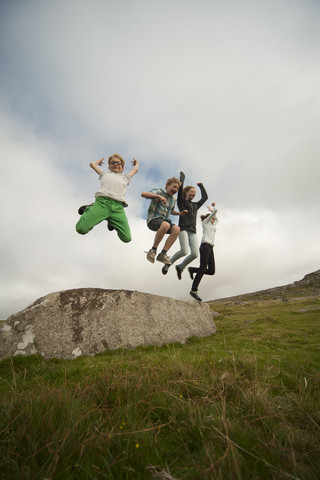 Vereinigtes Königreich, England, Cornwall, Kinder, die von einem Stein springen, lizenzfreies Stockfoto