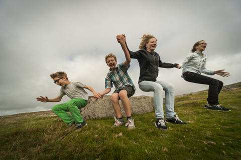 United Kingdom, England, Cornwall, Children jumping from stone stock photo