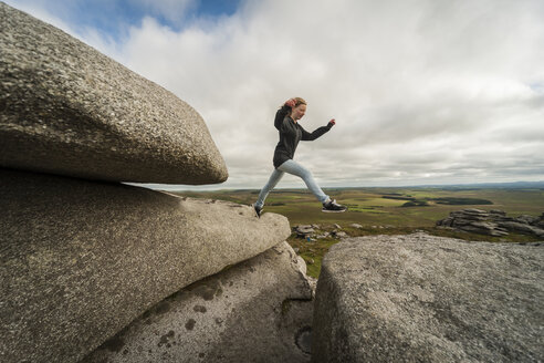 Vereinigtes Königreich, England, Cornwall, Bodmin Moor, Rough Tor, Felsformation, Mädchen springen - PAF001029