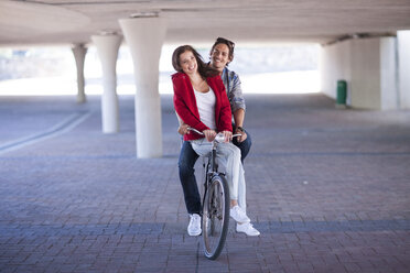 Happy couple riding bicycle in parking garage - ZEF007944