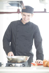 Lächelnde Köchin beim Kochen in der Küche - ZEF007955