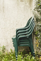 Stack of green garden chairs placed next to a wall - MELF000034