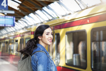 Germany, Berlin, young woman waiting in front of city train - FKF000741