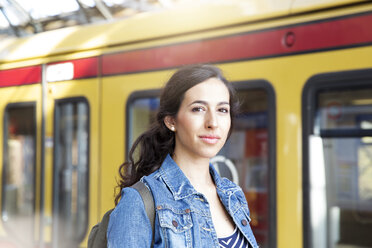 Germany, Berlin, portrait of young woman in front of city train - FK000742
