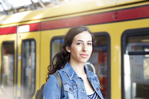 Deutschland, Berlin, Porträt einer jungen Frau vor einer Stadtbahn - FK000742