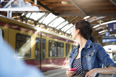 Germany, Berlin, young woman watching city train - FK000748