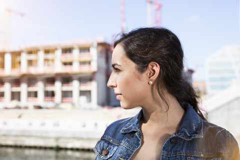 Deutschland, Berlin, Profil einer jungen Frau vor einer Baustelle, lizenzfreies Stockfoto