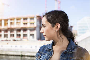 Germany, Berlin, profile of young woman in front of construction site - FKF000708