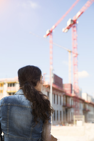 Deutschland, Berlin, junge Frau vor einer Baustelle, lizenzfreies Stockfoto