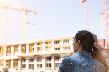 Germany, Berlin, young woman standing in front of construction site - FKF000711