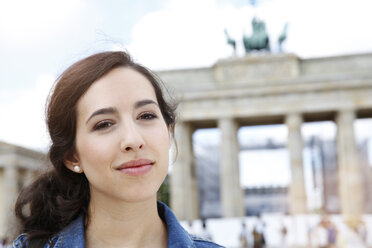 Germany, Berlin, portrait of young female tourist on city trip in front of Brandenburg Gate - FKF000714