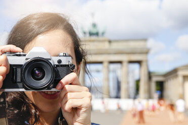 Deutschland, Berlin, Touristin vor dem Brandenburger Tor stehend und Betrachter fotografierend - FKF000717