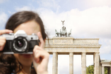 Deutschland, Berlin, Touristin vor dem Brandenburger Tor stehend und Betrachter fotografierend - FKF000718