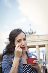 Germany, Berlin, portrait of young female tourist eating ice cream near Brandenburg Gate - FKF000723