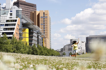 Deutschland, Berlin, glückliche junge Frau läuft auf einer Wiese in der Nähe des Potsdamer Platzes - FKF000735