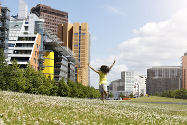 Germany, Berlin, happy young woman running on a meadow near Potsdam Square - FKF000739