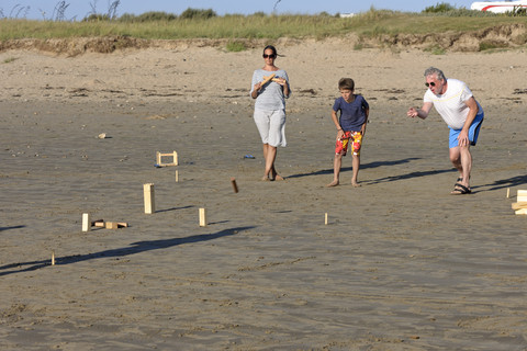 Eltern und Sohn spielen Kubb am Strand, lizenzfreies Stockfoto