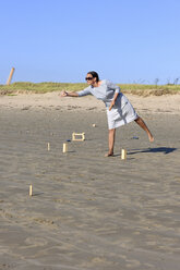 Frau spielt Kubb am Strand - LAF001190