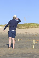Man playing Kubb on the beach - LAF001192