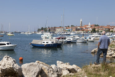 Slovenia, Istria, Izola, man at seashore with marina - WIF001140