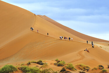 Namibia, Sossusvlei, Reisegruppe klettert auf Wüstendüne - MBF001218