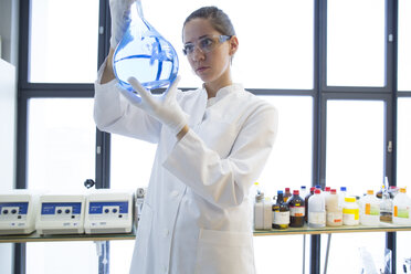 Young female scientist with glass bulb in a chemical lab - SGF000890